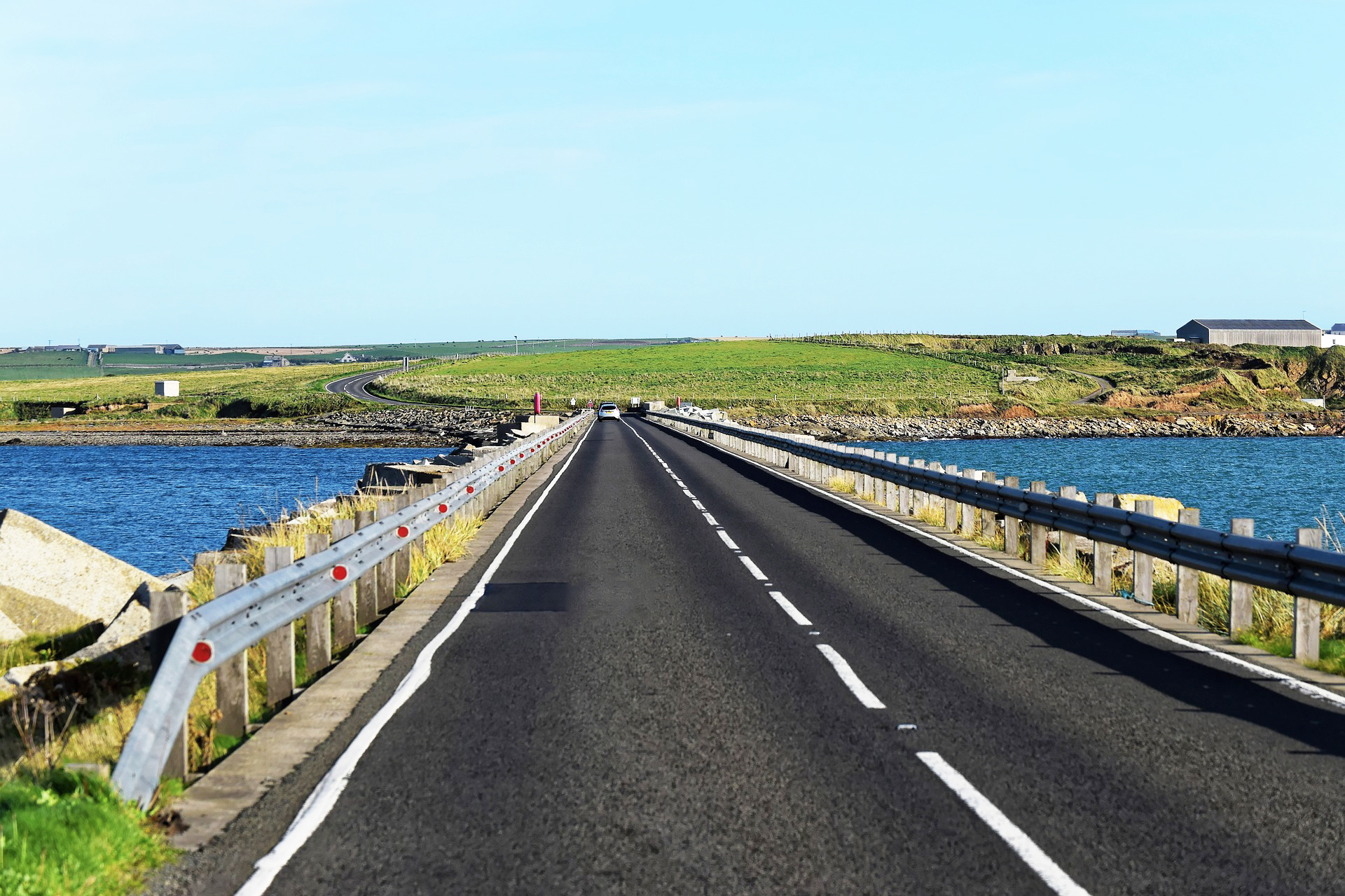 road through blue sea on orkney islands