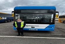 Kim standing infront of a bus