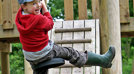 A photograph of a child on a zip wire in a playground