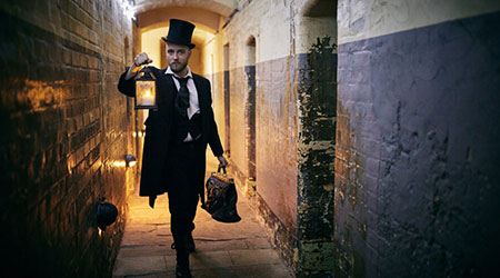 A photograph of a man in costume walking down a corridor in Oxford Castle and Prison