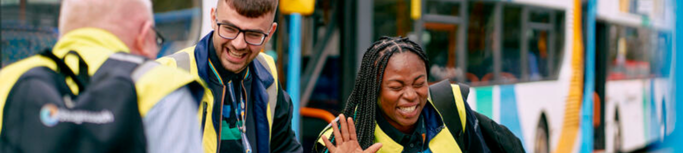 Three Stagecoach drivers laughing in front of a Stagecoach double decker bus