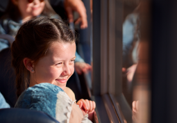 Young girl looking out of the window with her stuffed toy