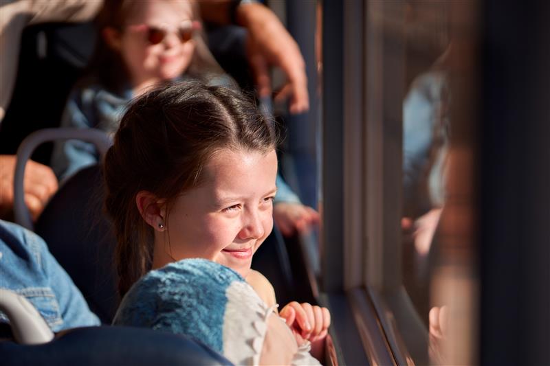 Young girl on a bus looking out the window with her cuddle toy